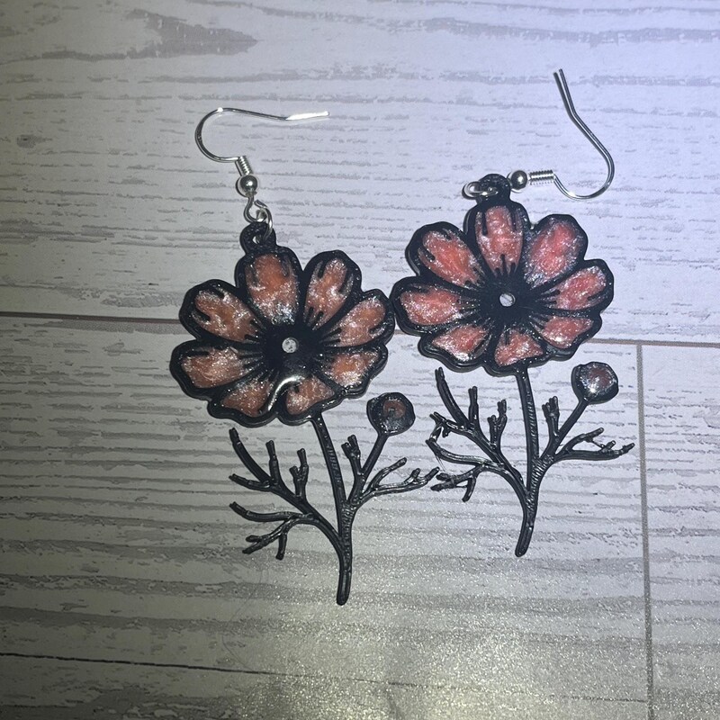Handmade pink resin flower earrings with a black floral outline